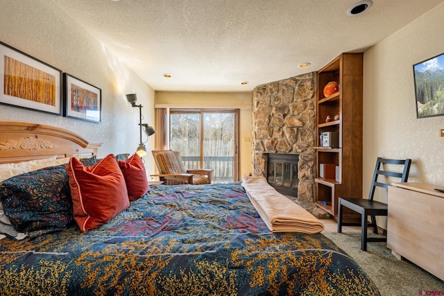 carpeted bedroom with a stone fireplace, access to outside, and a textured ceiling