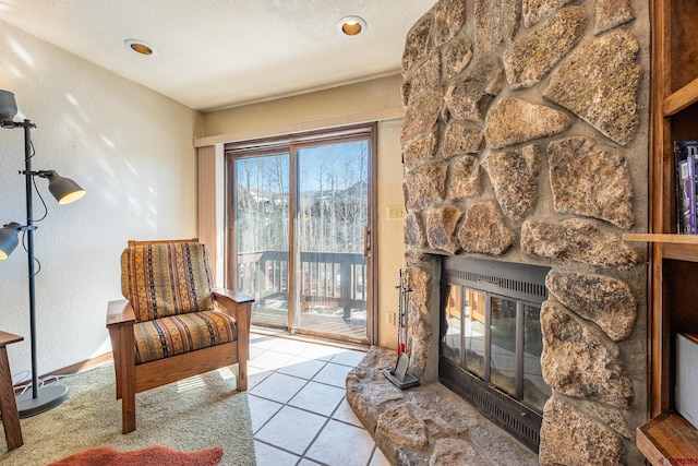 sitting room featuring a wealth of natural light, a fireplace, light tile floors, and a textured ceiling