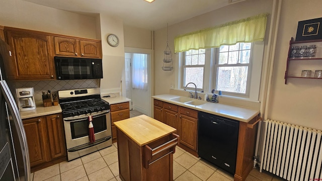 kitchen featuring sink, black appliances, light tile patterned flooring, decorative backsplash, and radiator heating unit