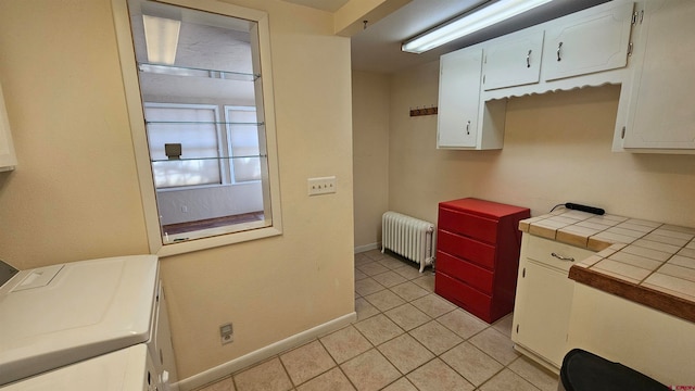 kitchen featuring radiator, light tile patterned floors, tile countertops, and white cabinets