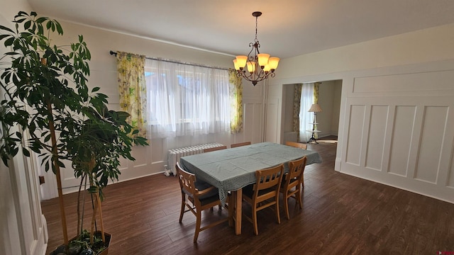 dining room featuring dark hardwood / wood-style floors, radiator heating unit, and a chandelier