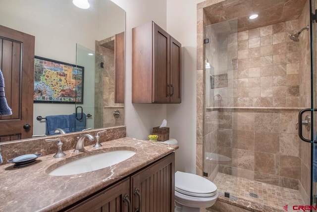 bathroom featuring vanity, toilet, and a shower with door