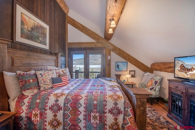 bedroom with hardwood / wood-style floors, wooden walls, access to outside, and lofted ceiling