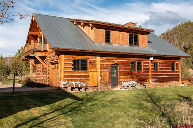 back of house with a balcony and a yard