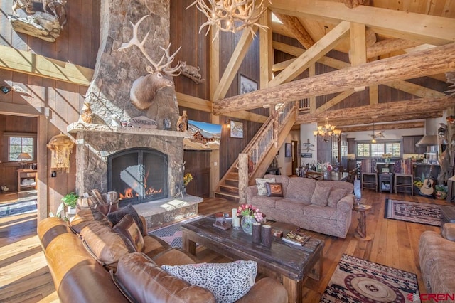 living room with beam ceiling, a stone fireplace, high vaulted ceiling, hardwood / wood-style floors, and wooden walls