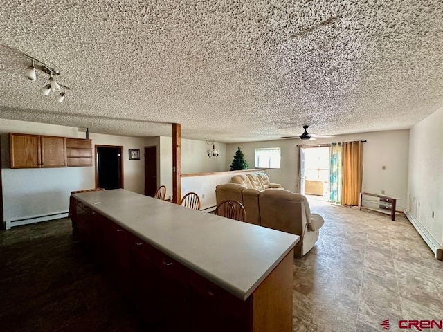 kitchen featuring ceiling fan, a baseboard heating unit, light tile floors, and a textured ceiling