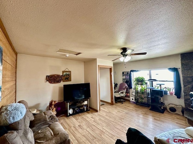 living room featuring ceiling fan, light wood-type flooring, and a textured ceiling