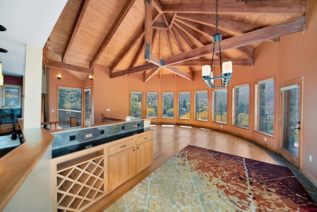 kitchen with a notable chandelier, plenty of natural light, light wood-type flooring, and beam ceiling