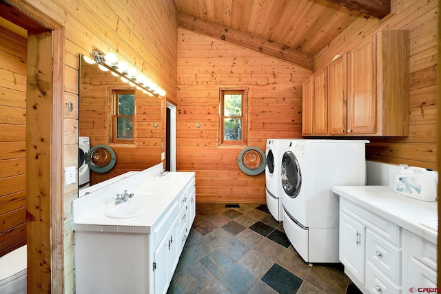 washroom featuring separate washer and dryer, dark tile flooring, wooden walls, wooden ceiling, and sink