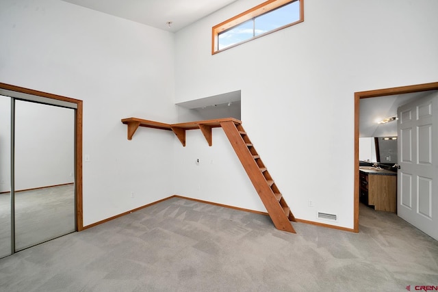 interior space featuring light colored carpet, sink, and a high ceiling