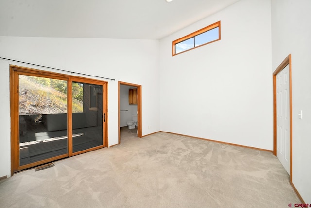 carpeted spare room featuring high vaulted ceiling and a wealth of natural light