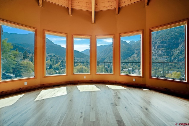 unfurnished sunroom with vaulted ceiling with beams and a mountain view