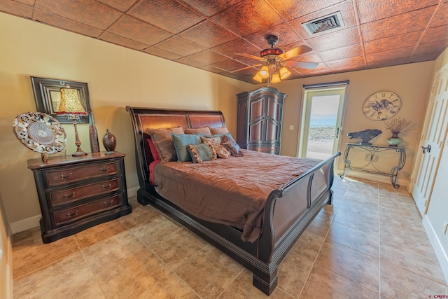 bedroom featuring a drop ceiling, ceiling fan, light tile flooring, and access to exterior