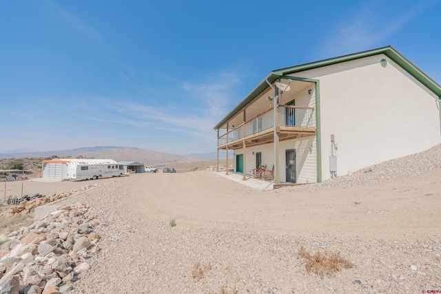 rear view of house featuring a mountain view and a balcony