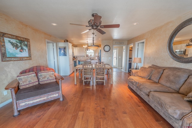 living room with sink, ceiling fan with notable chandelier, and hardwood / wood-style flooring