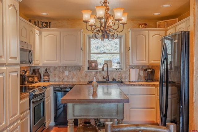 kitchen featuring sink, tasteful backsplash, white cabinetry, hanging light fixtures, and black appliances