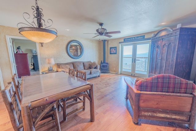 interior space featuring french doors, light hardwood / wood-style floors, ceiling fan, and a wood stove