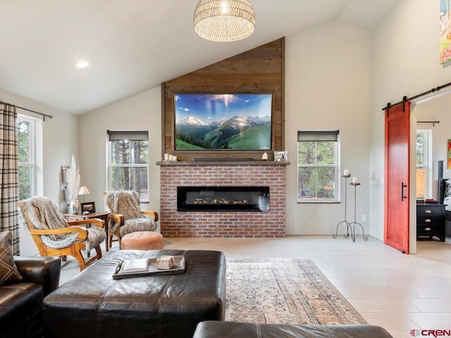 living room with a brick fireplace, hardwood / wood-style floors, a wealth of natural light, and a barn door