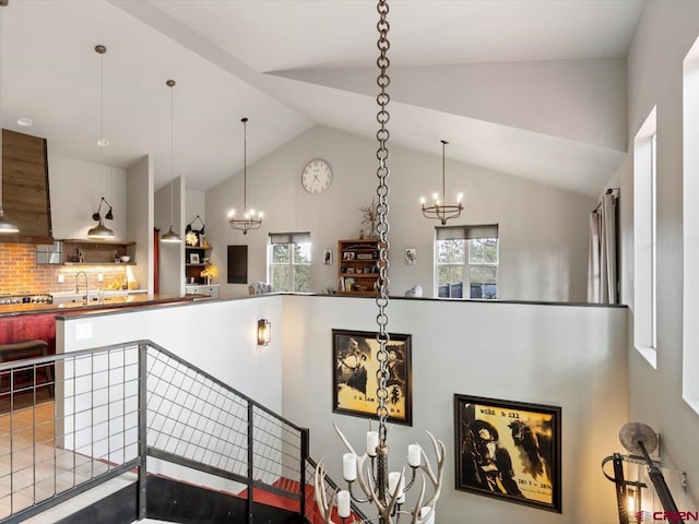 interior space featuring exhaust hood, tasteful backsplash, an inviting chandelier, and lofted ceiling