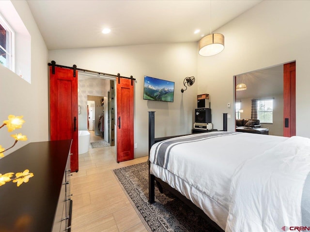 bedroom featuring high vaulted ceiling and a barn door