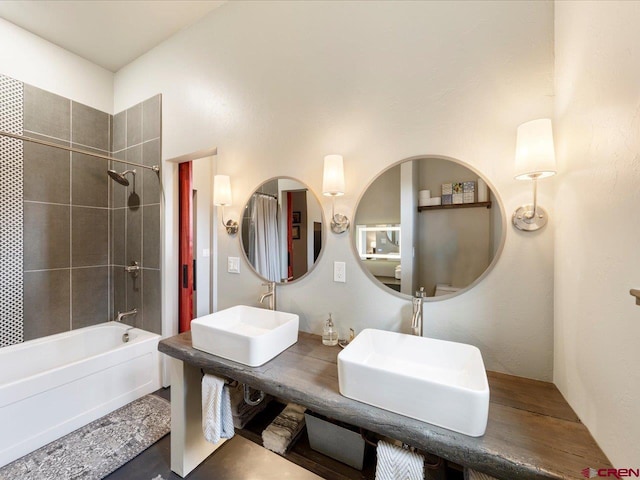 bathroom with double vanity and tiled shower / bath combo