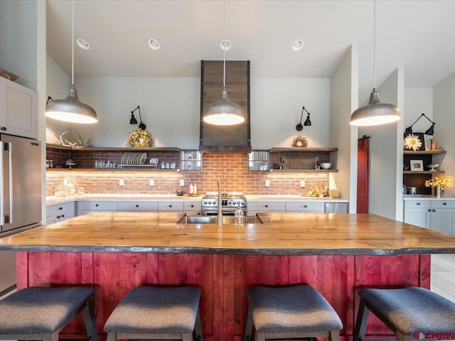 kitchen with backsplash, high end appliances, pendant lighting, and sink