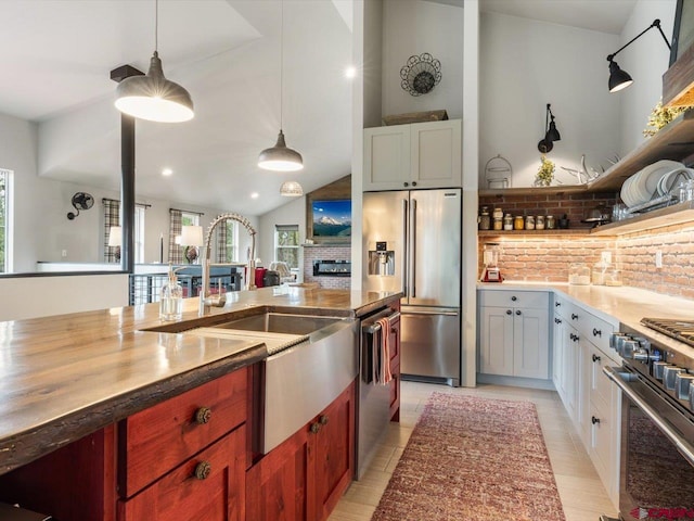 kitchen featuring appliances with stainless steel finishes, white cabinets, tasteful backsplash, vaulted ceiling, and pendant lighting