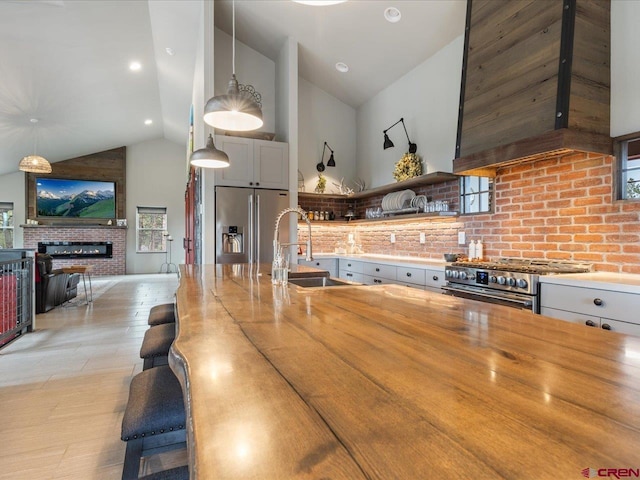 kitchen featuring high vaulted ceiling, decorative light fixtures, appliances with stainless steel finishes, extractor fan, and sink