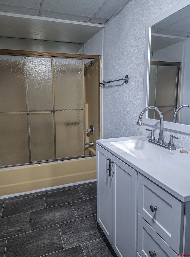 bathroom featuring a drop ceiling, vanity with extensive cabinet space, combined bath / shower with glass door, and tile flooring