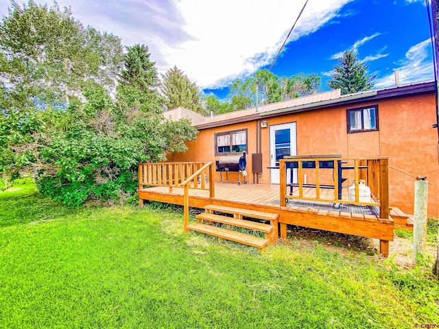 rear view of house with a deck and a lawn