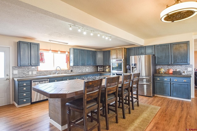 kitchen with appliances with stainless steel finishes, a center island, and tasteful backsplash