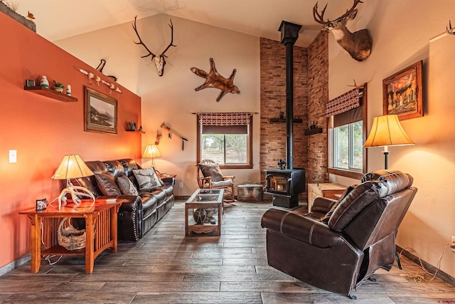 living room featuring a wealth of natural light, a wood stove, wood-type flooring, and high vaulted ceiling