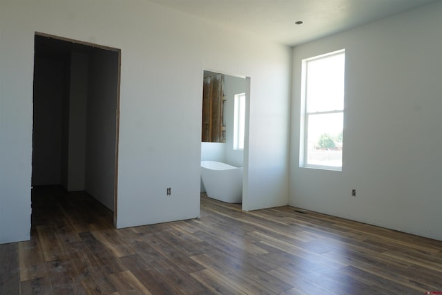 unfurnished bedroom with dark hardwood / wood-style flooring, ensuite bathroom, and multiple windows