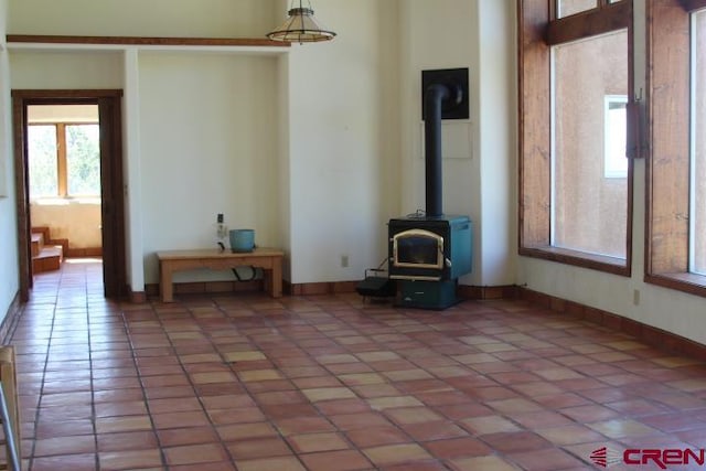 unfurnished living room featuring light tile patterned floors and a wood stove