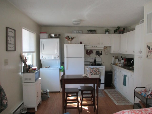 kitchen with white appliances, dark hardwood / wood-style flooring, stacked washer and dryer, white cabinets, and range hood