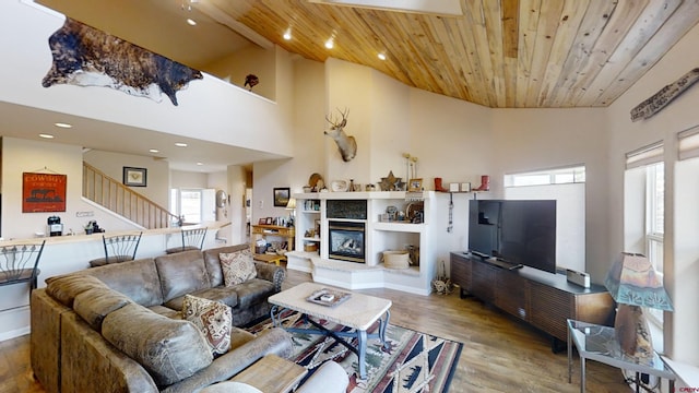 living room featuring wood ceiling, hardwood / wood-style floors, a towering ceiling, and a multi sided fireplace