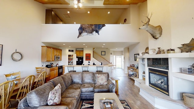 living room featuring beamed ceiling, wood-type flooring, a towering ceiling, and a fireplace