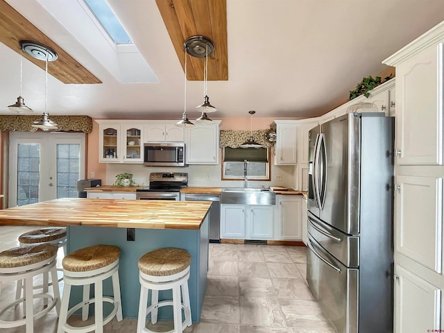 kitchen featuring white cabinets, sink, appliances with stainless steel finishes, and wood counters