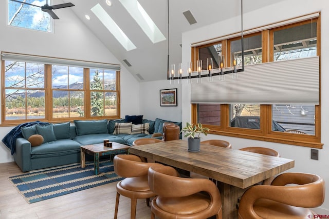 dining space with a skylight, high vaulted ceiling, ceiling fan, and wood-type flooring