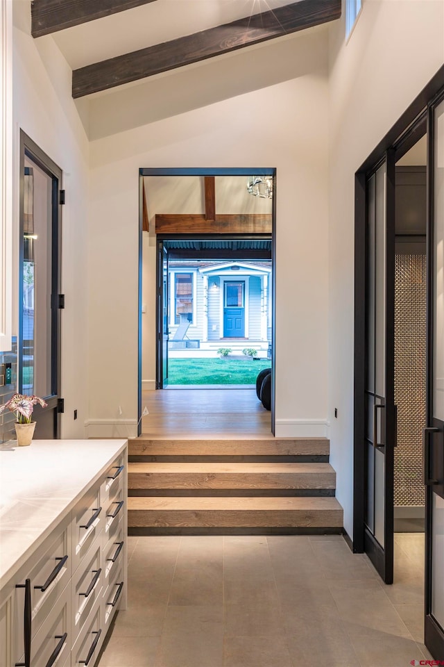 hallway with a healthy amount of sunlight, vaulted ceiling with beams, and light hardwood / wood-style flooring