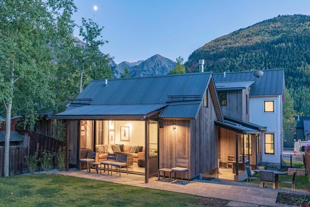 rear view of house featuring a mountain view, outdoor lounge area, a lawn, and a patio area