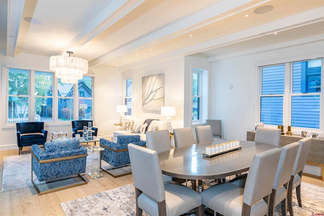 dining space with a notable chandelier, beamed ceiling, plenty of natural light, and light wood-type flooring