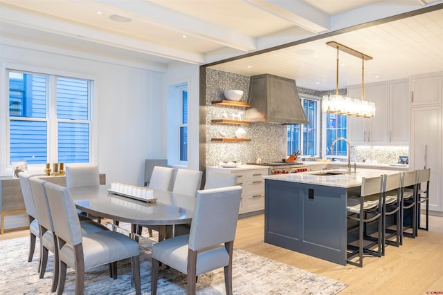 interior space with beamed ceiling, sink, an inviting chandelier, and light wood-type flooring