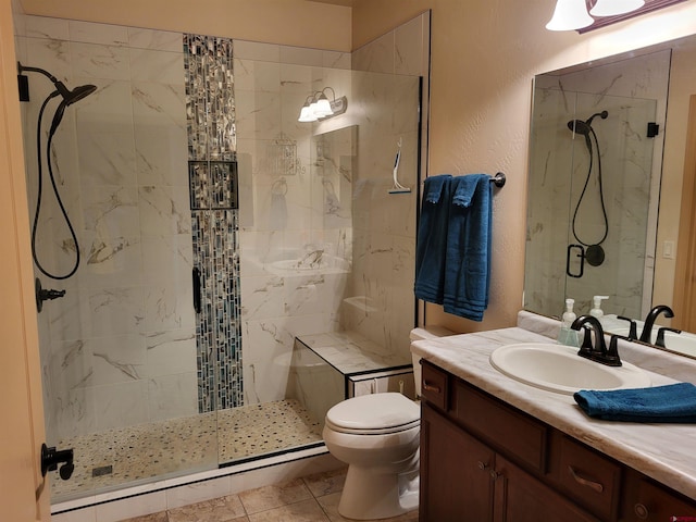 bathroom featuring vanity, tile patterned flooring, toilet, and tiled shower