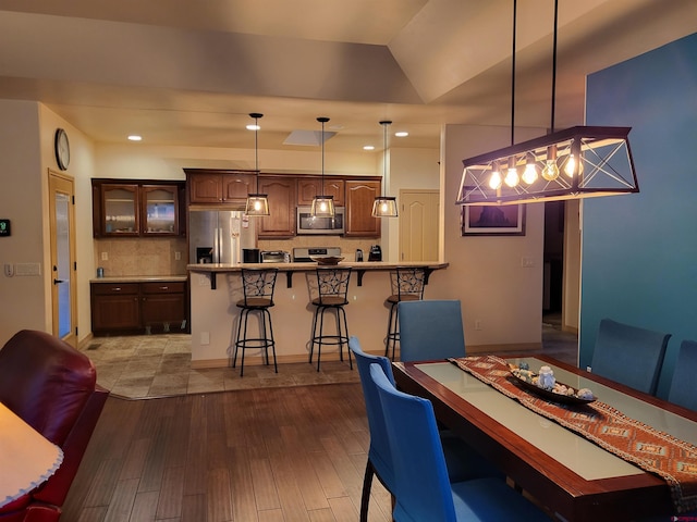 dining room with vaulted ceiling and light wood-type flooring