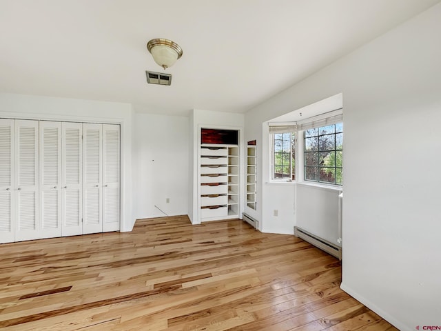 unfurnished bedroom with a baseboard radiator and light hardwood / wood-style floors