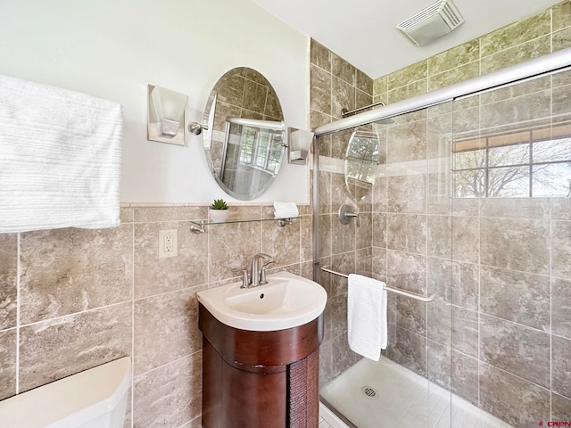 bathroom with vanity with extensive cabinet space, an enclosed shower, backsplash, and tile walls