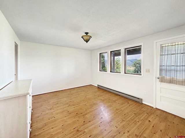 unfurnished room featuring light hardwood / wood-style flooring and a baseboard radiator