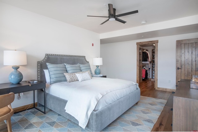 bedroom with ceiling fan, a walk in closet, a closet, and hardwood / wood-style flooring