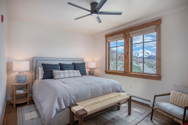 bedroom featuring a baseboard heating unit, ceiling fan, and hardwood / wood-style flooring